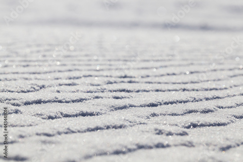 Snow surface, winter - snow drifts after the past snowfall. On the surface irregularities from strong winds were formed. Photo close-up at an angle with a shallow depth of field