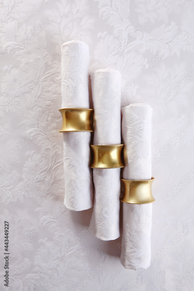 Festive table setting.Napkins made of cotton with brass rings.The concept of holidays.Top view.White tablecloth with a textured pattern.A copy of the space. Festive table setting.Napkins made of cotton with brass rings.The concept of holidays.Top view.White tablecloth with a textured pattern.A copy of the space.