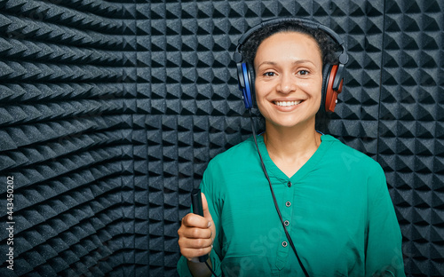Portrait adult woman while hearing check-up at soundproof audiometric cabin using audiometry headphones and audiometer photo
