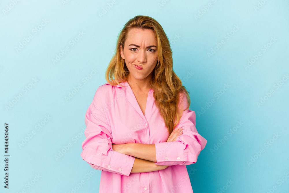 Caucasian woman isolated on blue background frowning face in displeasure, keeps arms folded. Caucasian woman isolated on blue background frowning face in displeasure, keeps arms folded.