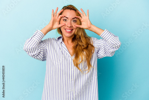 Caucasian woman isolated on blue background keeping eyes opened to find a success opportunity.