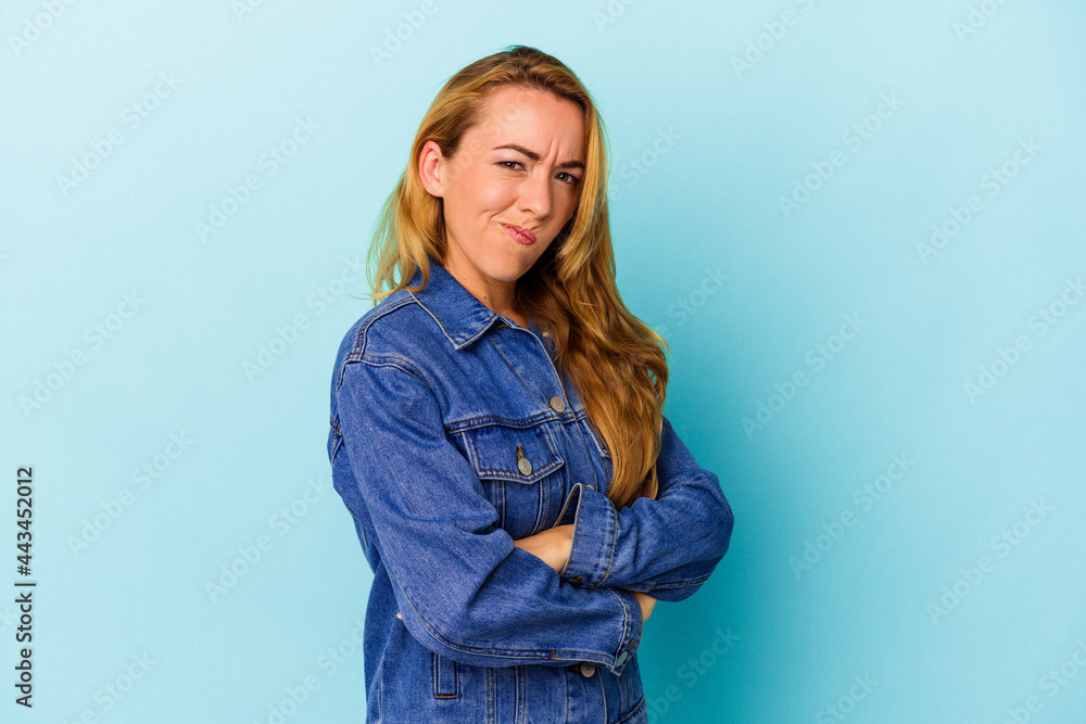Caucasian woman isolated on blue background frowning face in displeasure, keeps arms folded. Caucasian woman isolated on blue background frowning face in displeasure, keeps arms folded.