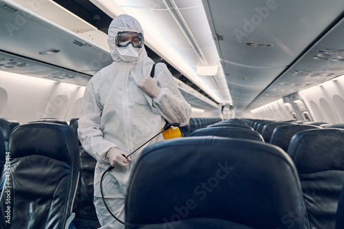 Concentrated male worker sanitizing the passenger cabin photo