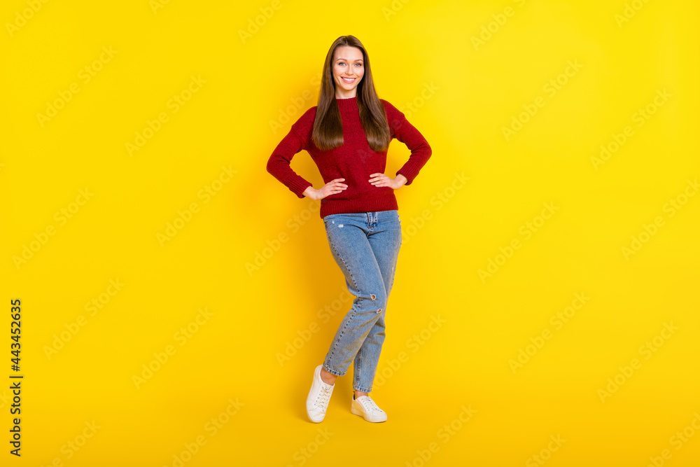 Full size photo of pretty young lady stand wear sweater jeans isolated on vivid yellow color background Full size photo of pretty young lady stand wear sweater jeans isolated on vivid yellow color background