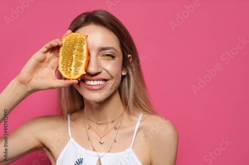Young woman with fresh kiwano on pink background, space for text. Exotic fruit