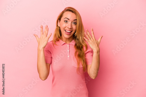 Caucasian blonde woman isolated on pink background showing number ten with hands.
