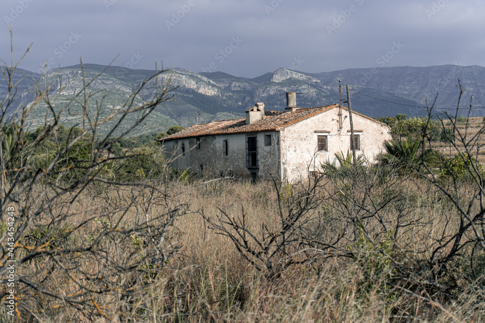 Old abandoned farmhouse in a field, with mountains in the background. Old abandoned farmhouse in a field, with mountains in the background.
