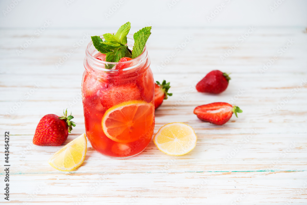 Cold summer strawberry lemonade in a jar on a white background, selective focus Cold summer strawberry lemonade in a jar on a white background, selective focus