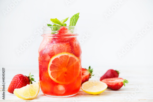 Cold summer strawberry lemonade in a jar on a white background, selective focus