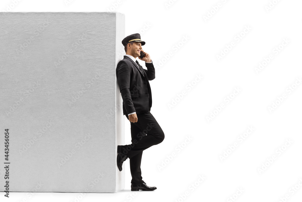 Full length profile shot of a chauffeur leaning on a wall and using a mobile phone Full length profile shot of a chauffeur leaning on a wall and using a mobile phone