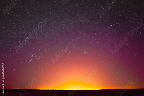 Colorful Night Sky With Glowing Stars Background Backdrop. Sky Gradient. Sunset  Sunrise Lights And Colourful Night Starry Sky In Yellow Pink Magenta Orange Purple Colors. Dark Ground Silhouette. Copy