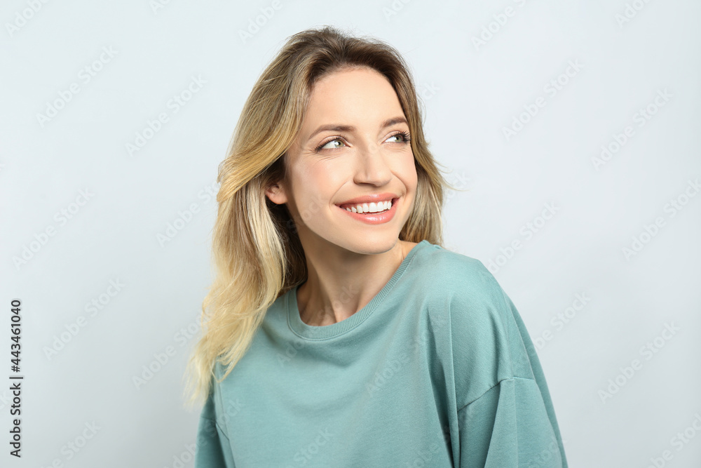 Portrait of happy young woman with beautiful blonde hair and charming smile on light background Portrait of happy young woman with beautiful blonde hair and charming smile on light background