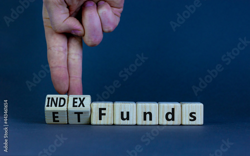 Index funds vs ETF symbol. Businessman turns a cube and changes words 'ETF, Exchange-Traded Fund' to 'Index funds. Beautiful grey background, copy space. Business and ETF vs index funds concept.
