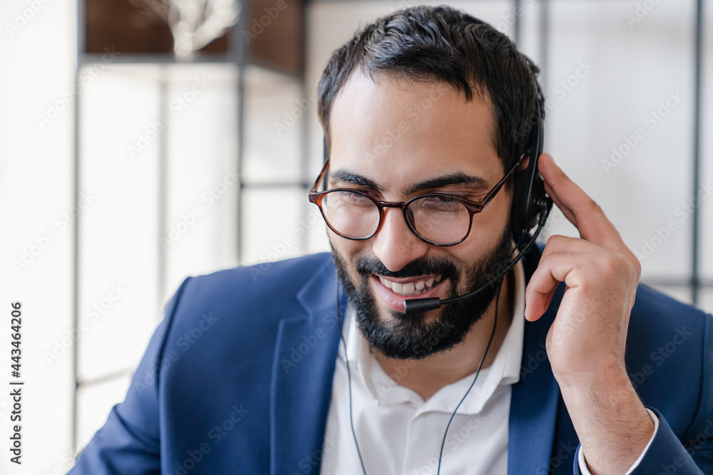 Confident Arabian young businessman in headset speaking on conference call on laptop, male call center agent operator telemarketer customer service support consulting remotely Confident Arabian young businessman in headset speaking on conference call on laptop, male call center agent operator telemarketer customer service support consulting remotely