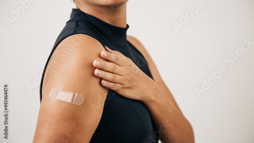 vaccinated woman with a band-aid on her arm, showing where she received the injection.