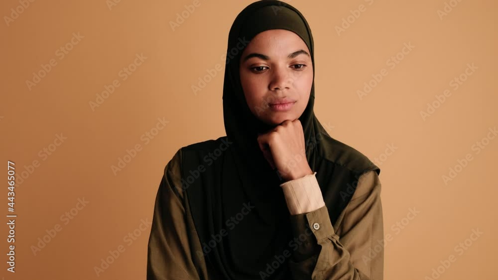 A beautiful arabian woman is thinking about something standing isolated over beige background A beautiful arabian woman is thinking about something standing isolated over beige background
