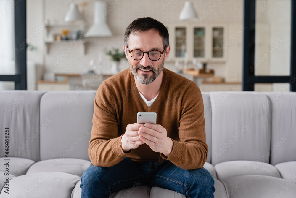 Front view caucasian middle-aged man using smart phone for web browsing, social media, checking e-mails, e-banking, booking tickets online on quarantine. Front view caucasian middle-aged man using smart phone for web browsing, social media, checking e-mails, e-banking, booking tickets online on quarantine.