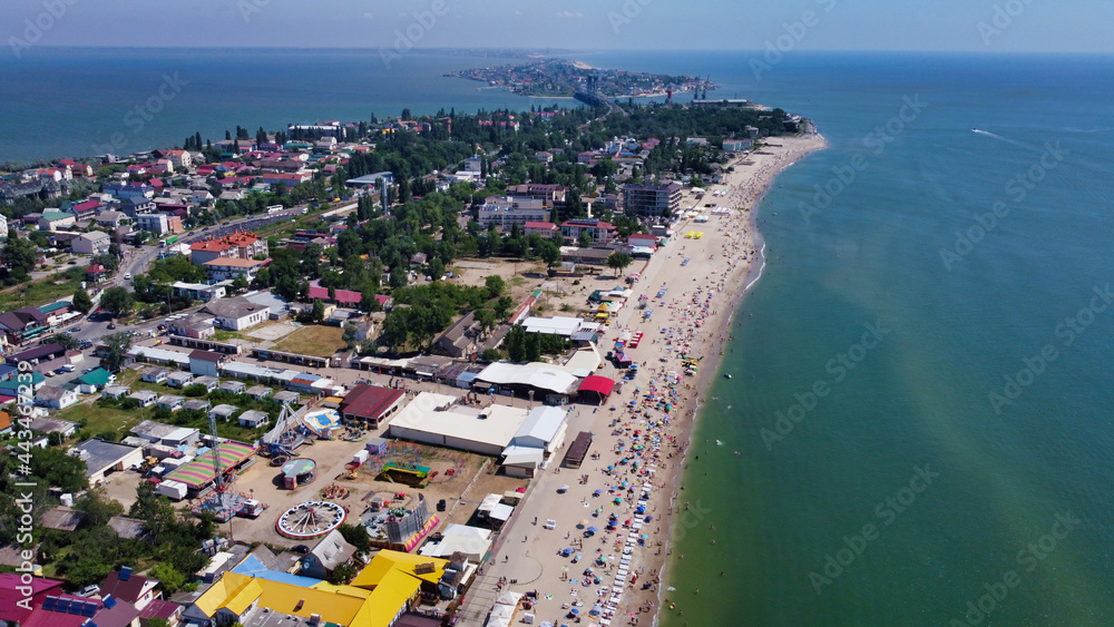 View of the Black Sea and sandy beach. in Zatoka. Vacationers on the beach. Houses on the peninsula and estuary. Ukraine. Europe	