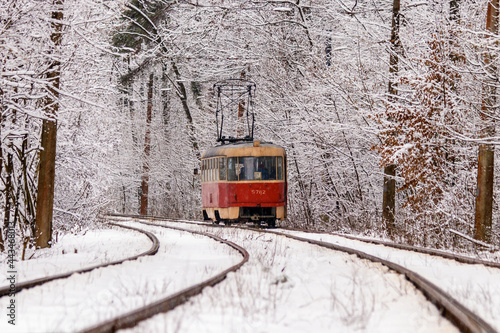 An old tram moving through a winter forest