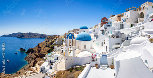 Panorama of the whitewashed houses and blue domed churches of the village Oia, Santorini island, Greece, during summer time