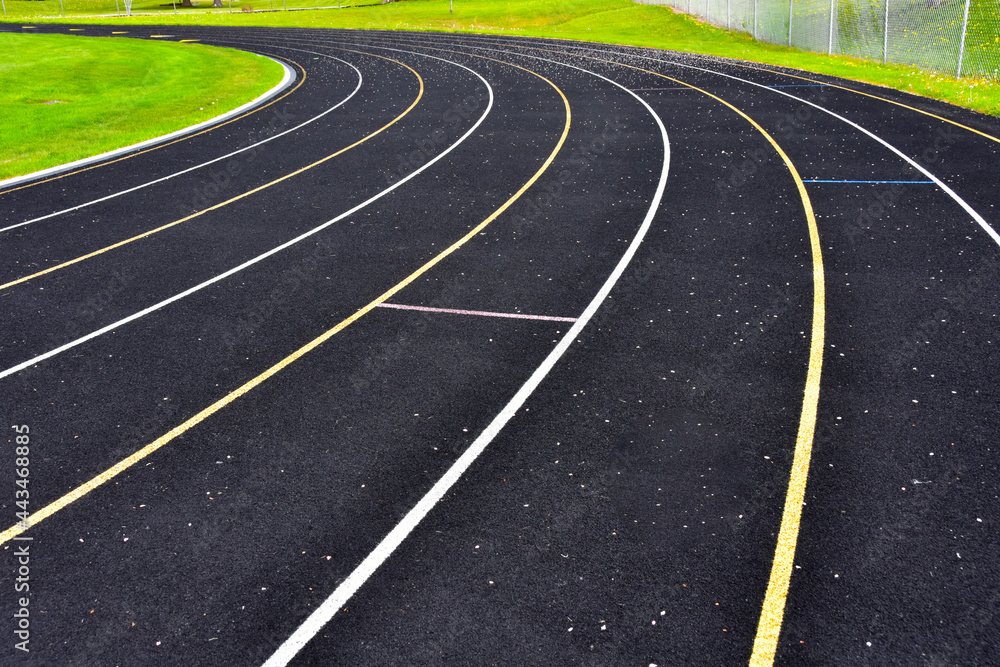 Curved portion of athletic running track with lane markers painted on surface.

