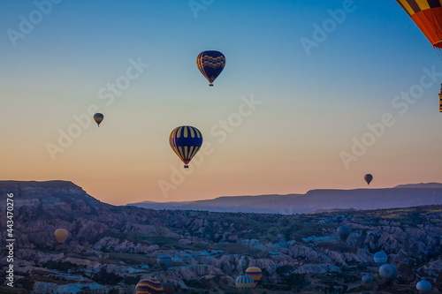 Hot air balloons flying over the valley at Cappadocia, Turkey. Goreme Balloon Festival. Beautiful hot air balloons take off at sunrise. Hot air balloons in the blue sky © decorator