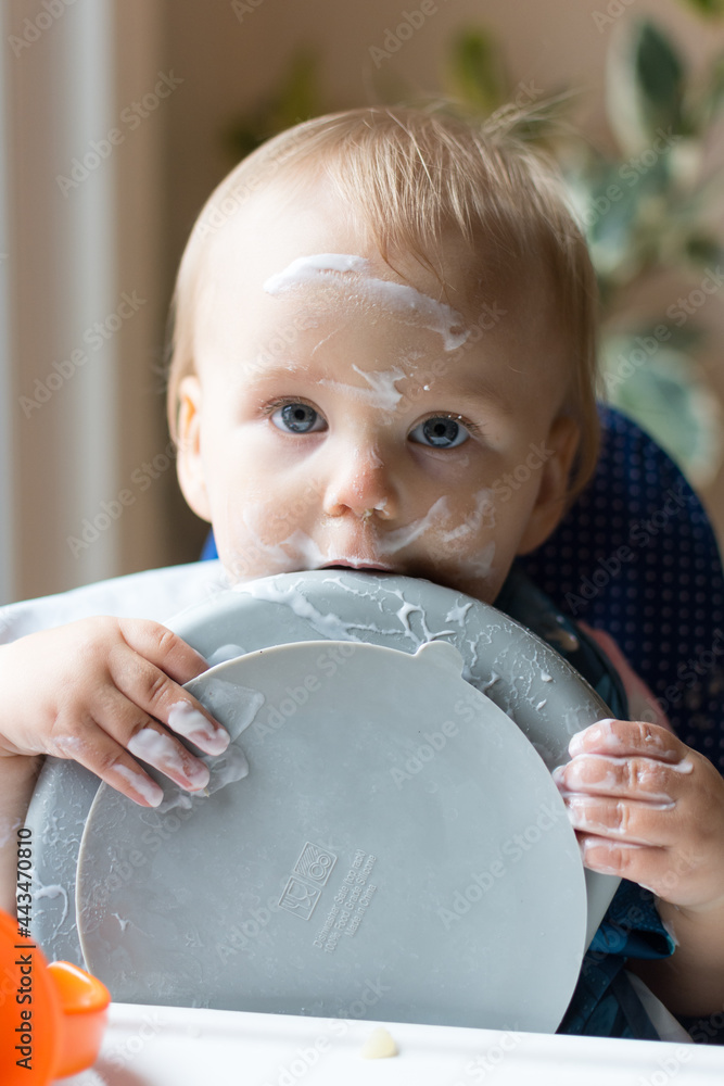 Fotka „13 month old baby holding plate and licking it after eating