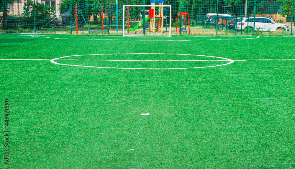 Fototapeta premium Soccer field with artificial green grass near the school. Amateur football field. Sunny summer day