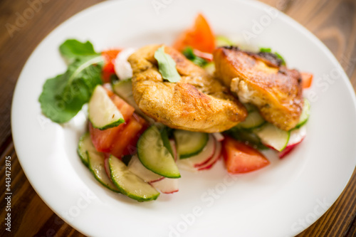 fried chicken fillet with fresh cucumbers, tomatoes and radishes in a plate