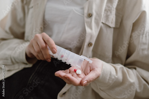 Young woman take pills from organizer box