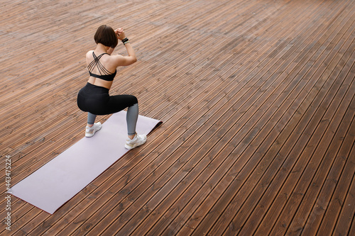 Sportswoman do sit ups on fitness mat on wood area