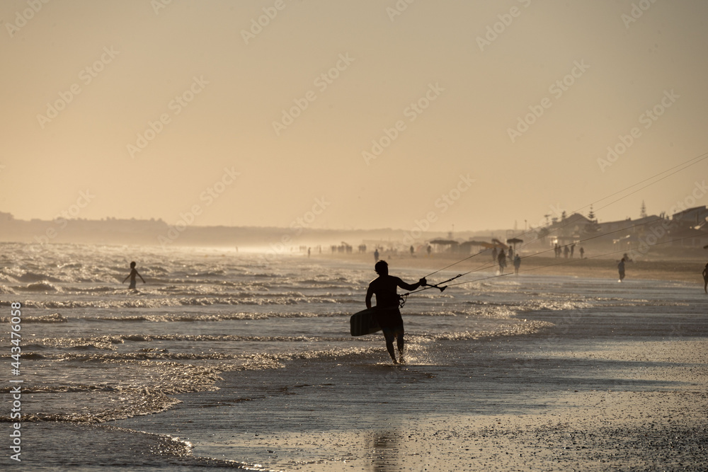 silhouette man with kitesurf kite in the sunset of the beach of huelva