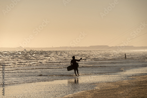 silhouette man with kitesurf kite in the sunset of the beach of huelva