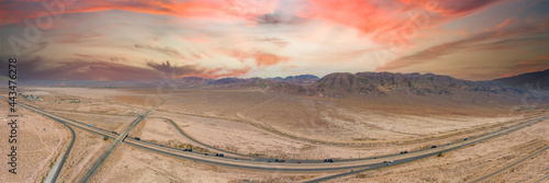 a stunning aerial panoramic shot of majestic mountain ranges in a vast desert land with powerful clouds with freeways filled with cars in Yermo California USA photo