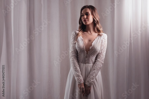 Beautiful young bride with light make-up in white dress  in an exquisite interior 