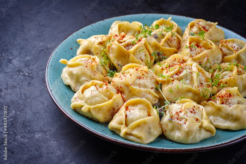 Traditional steamed Kazakh manti garnished with mincemeat and sumah served as close-up on a Nordic design plate with copy space left Traditional steamed Kazakh manti garnished with mincemeat and sumah served as close-up on a Nordic design plate with copy space left