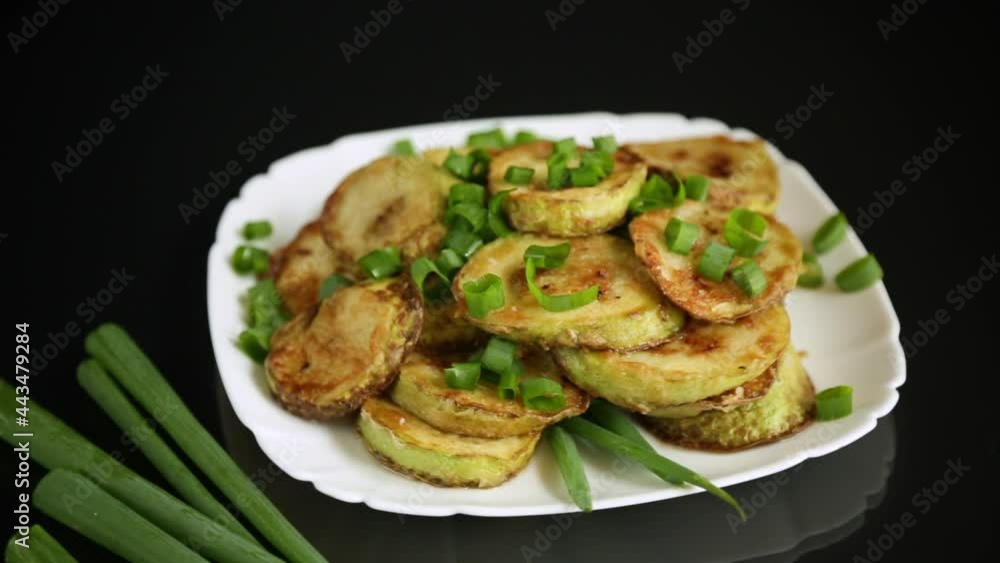 fried zucchini in circles with fresh herbs in a plate on a black fried zucchini in circles with fresh herbs in a plate on a black