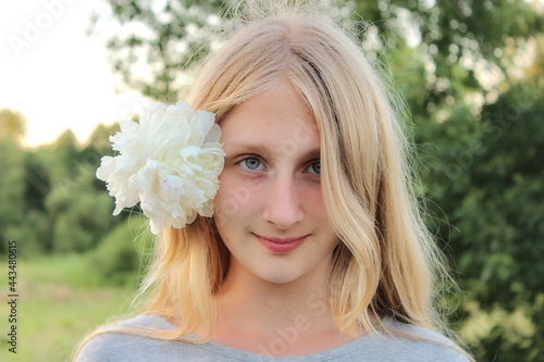 Young girl with white flower in her hair in the garden