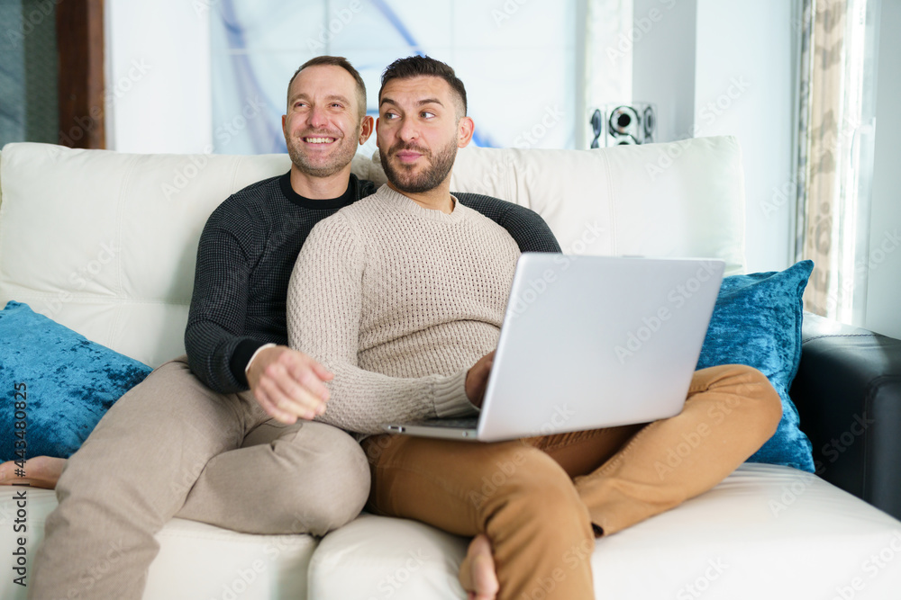 Gay couple consulting their travel plans together with a laptop. Gay couple consulting their travel plans together with a laptop.