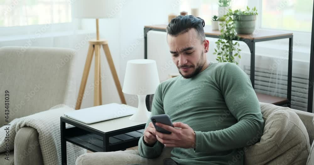 Young man using mobile phone on sofa at home Young man using mobile phone on sofa at home
