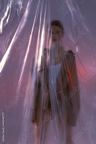 Fashion portraits of a stylish girl with makeup on a polyethylene background