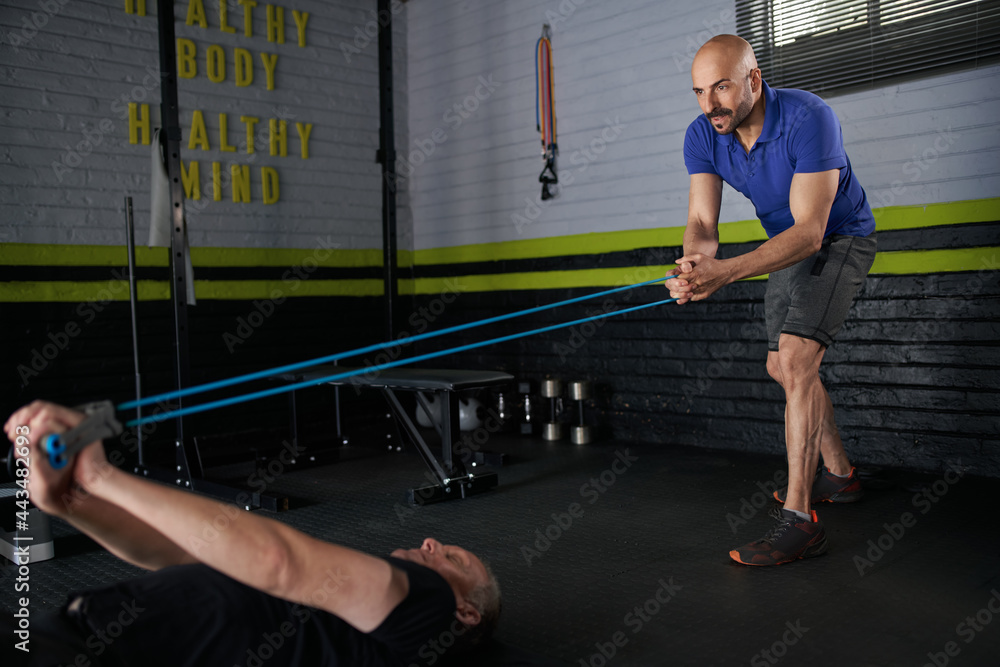 Fototapeta premium Personal trainer holding resistance bands. Mature man exercising