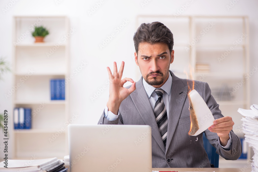 Young male employee unhappy with excessive work in the office Young male employee unhappy with excessive work in the office