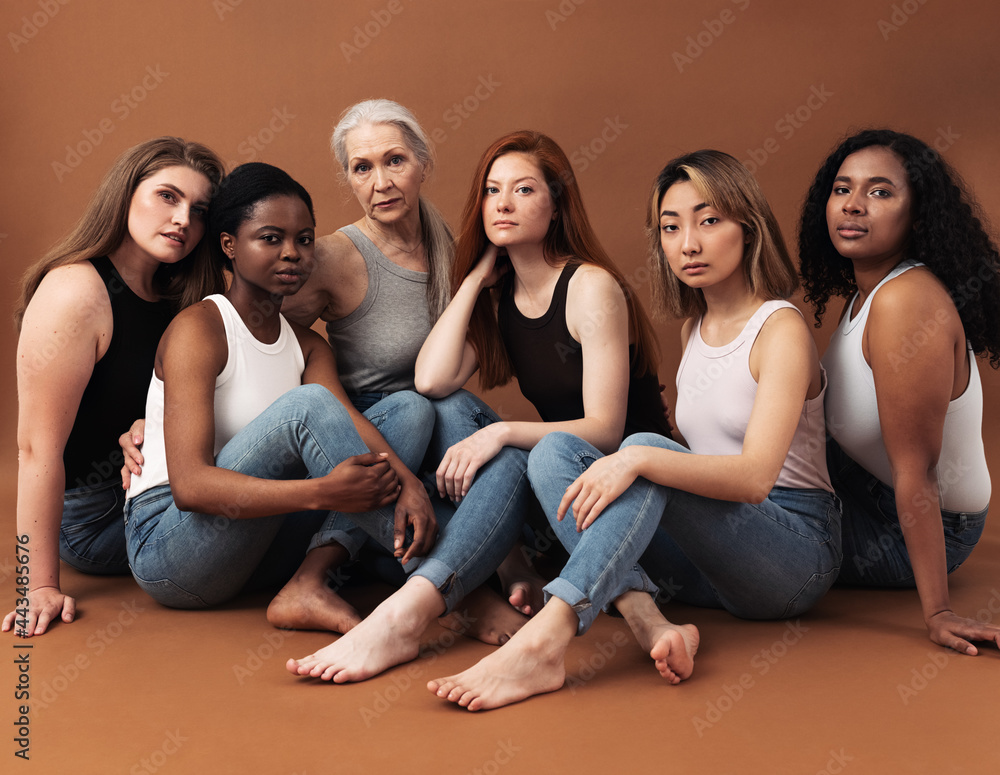 © Artem Varnitsin - Diverse women in casuals sitting on brown background. Multi-ethnic group of females looking at camera in studio.