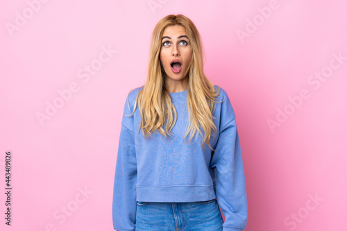 Young Uruguayan blonde woman over isolated pink background looking up and with surprised expression