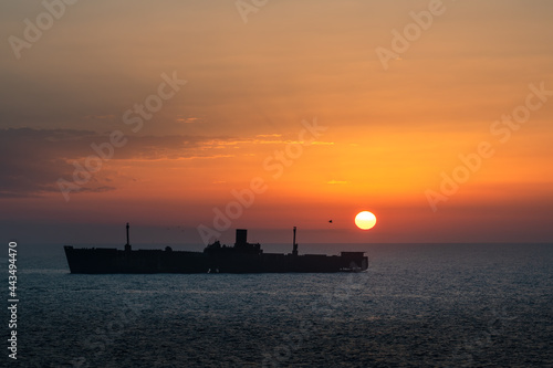 Beautiful sunrise over shipwreck and sea. Morning ship silhouette