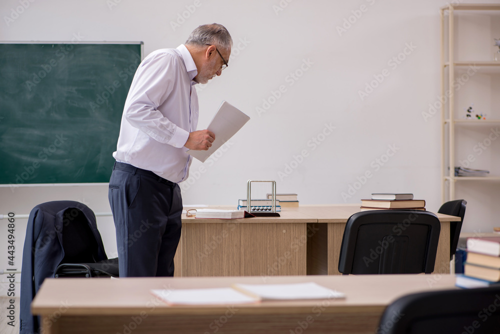 Old male teacher in front of blackboard Old male teacher in front of blackboard