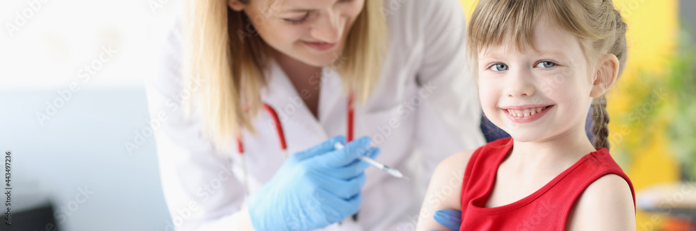 Doctor injecting medicine into shoulder of little girl in clinic Doctor injecting medicine into shoulder of little girl in clinic
