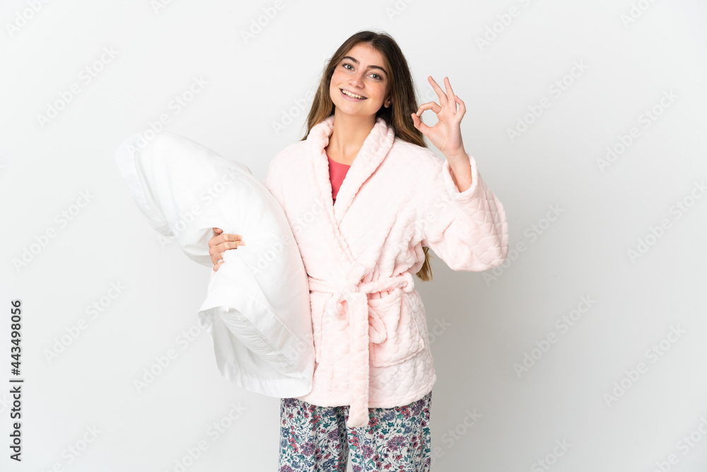 Young caucasian woman isolated on white background in pajamas and showing ok sign with fingers Young caucasian woman isolated on white background in pajamas and showing ok sign with fingers