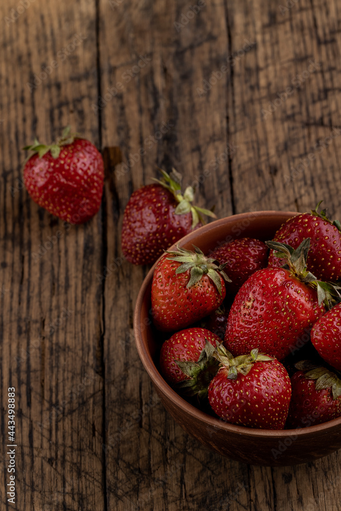 rustic red strawberry at bowl on a wooden table top. above view
